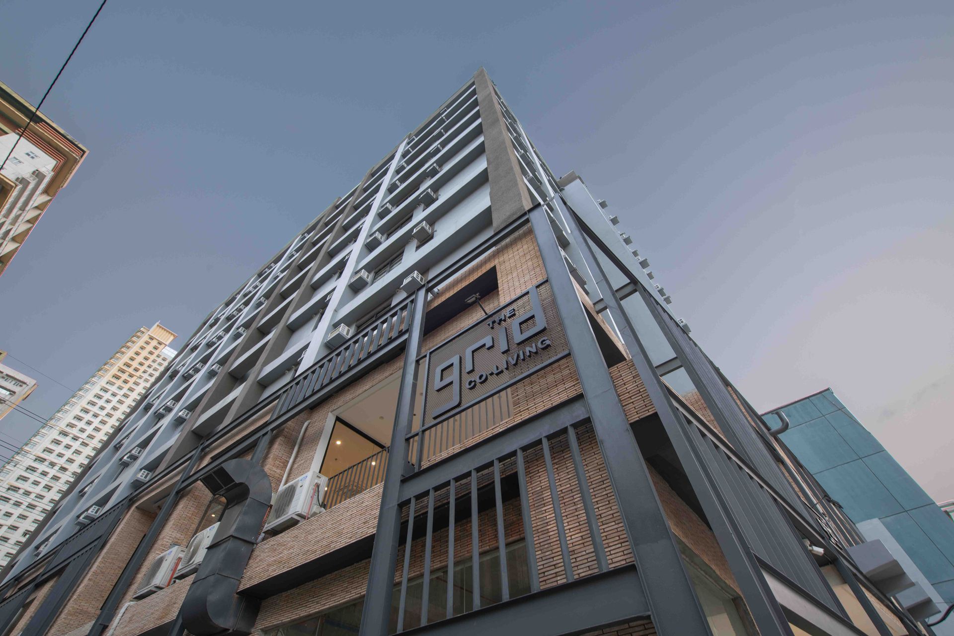 Low-angle view of a modern high-rise building with dark metal framing and glass windows against the sky