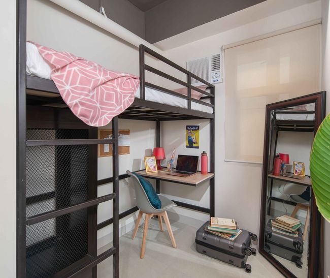 A bedroom with a bunk bed and a desk with a laptop on it.