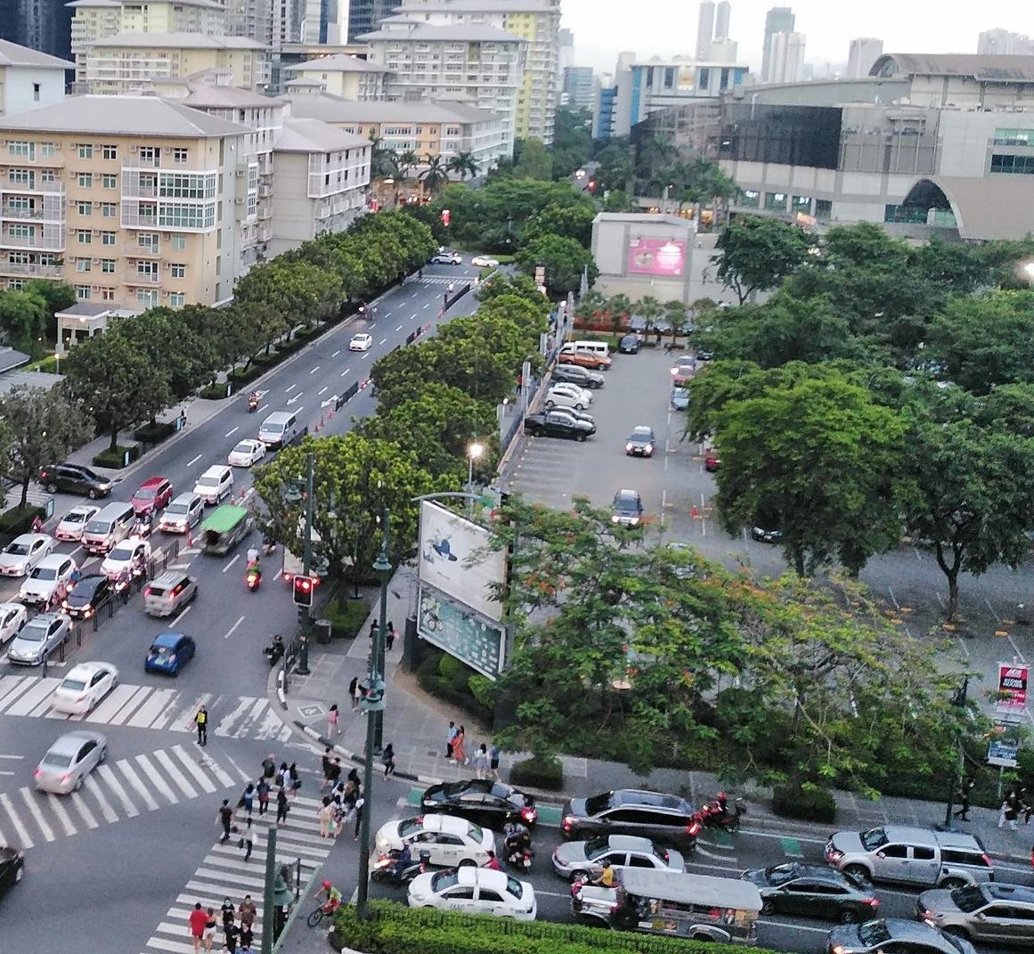 Busy city street with cars, pedestrians, and tall buildings.
