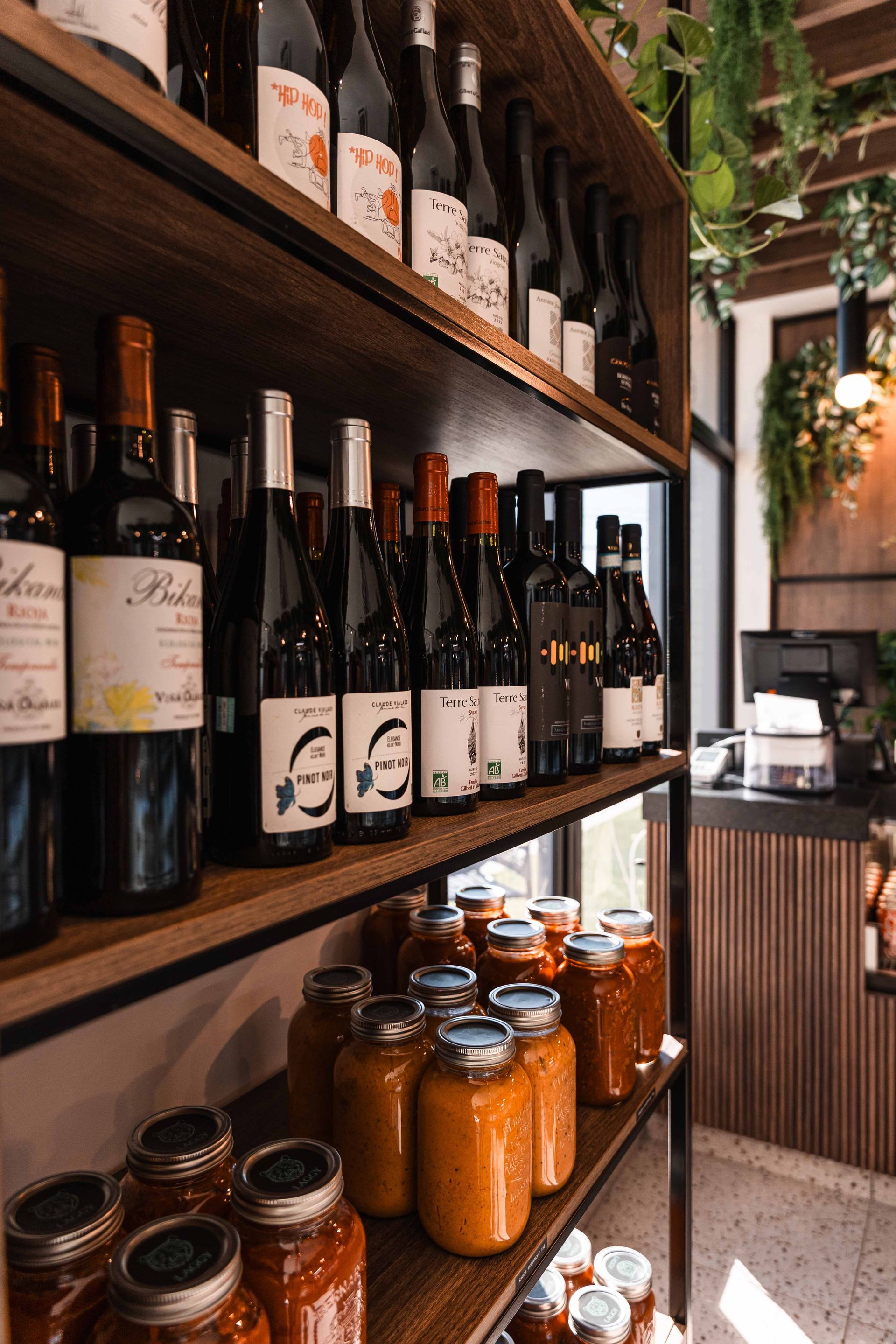 Bouteilles de vin et bocaux de nourriture sur des étagères en bois dans un magasin.