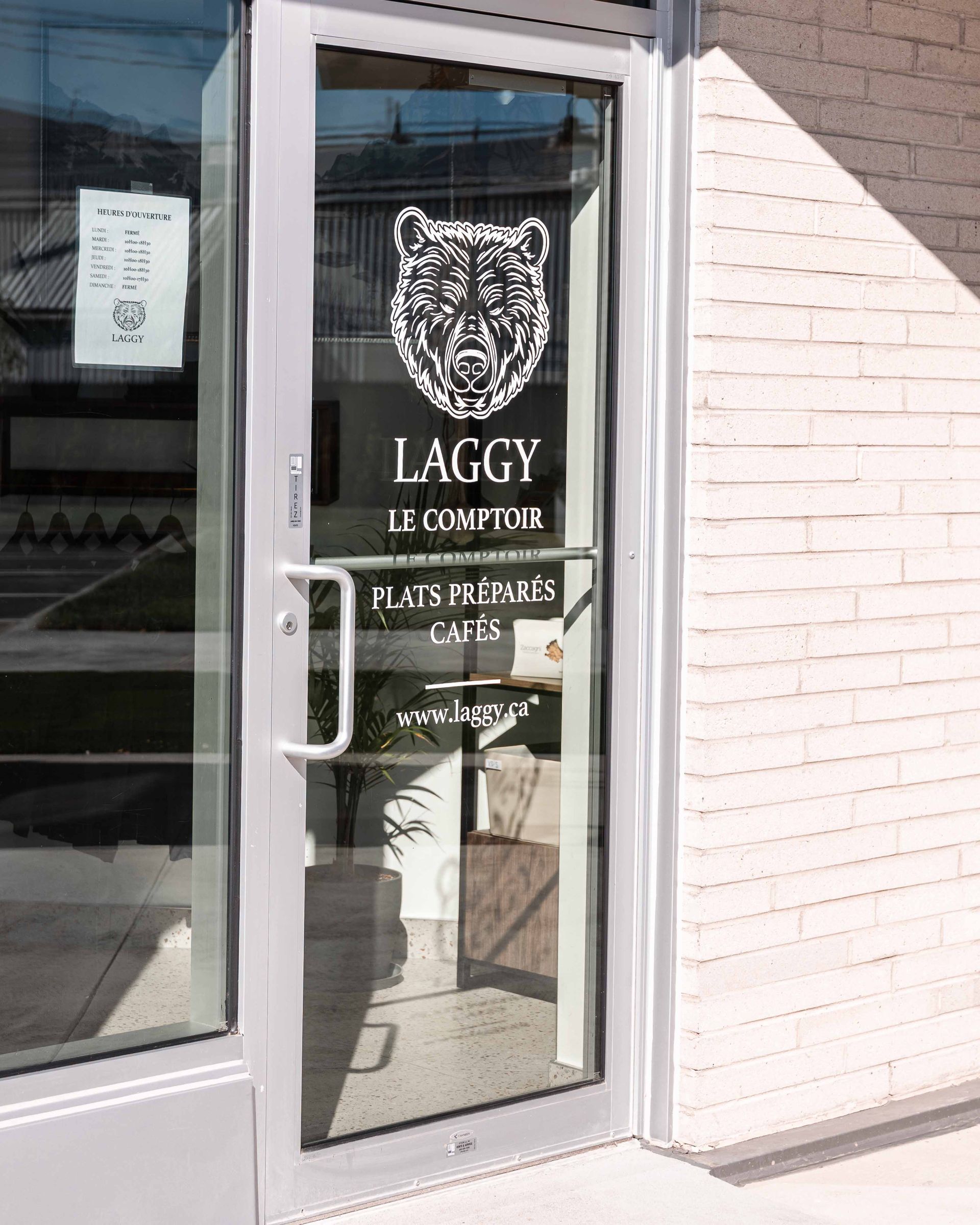 Porte vitrée avec une enseigne blanche représentant une tête de jaguar et l'inscription « LAGGY EL COMPTOR ».