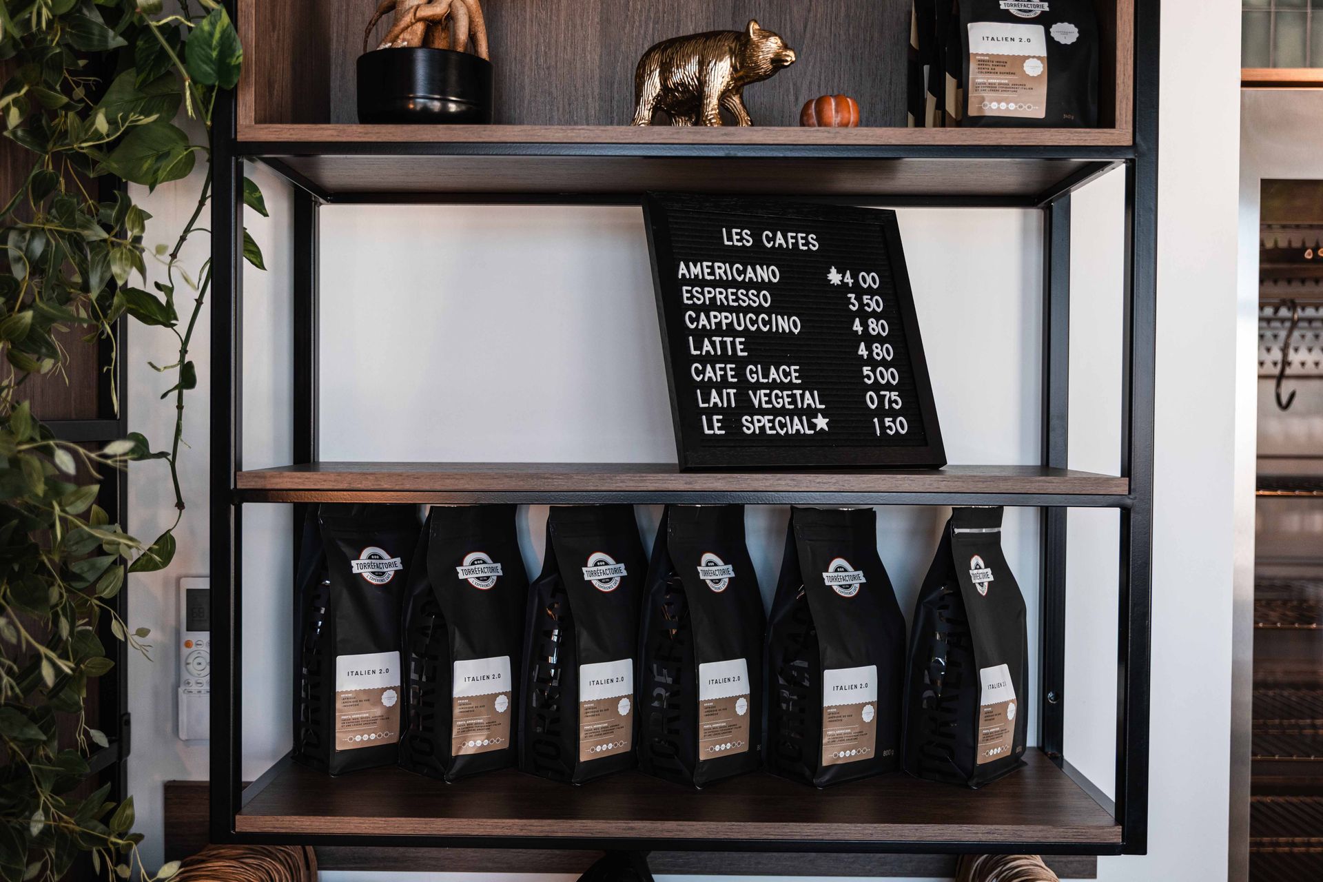 Des étagères présentent des sachets de café, un menu et des éléments de décoration à l'intérieur d'un café.