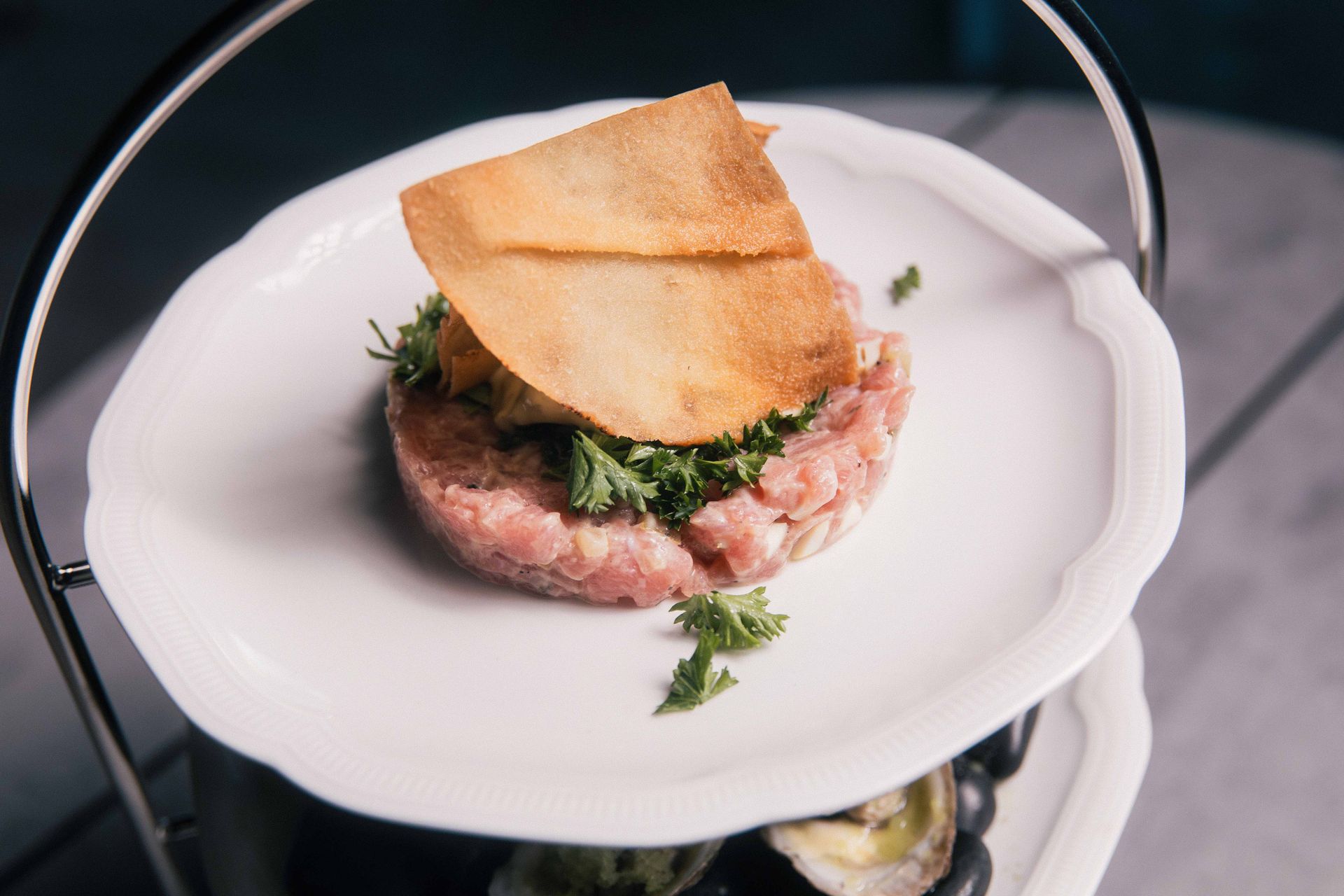 Tartare de bœuf accompagné d'un cracker croustillant sur une assiette blanche.