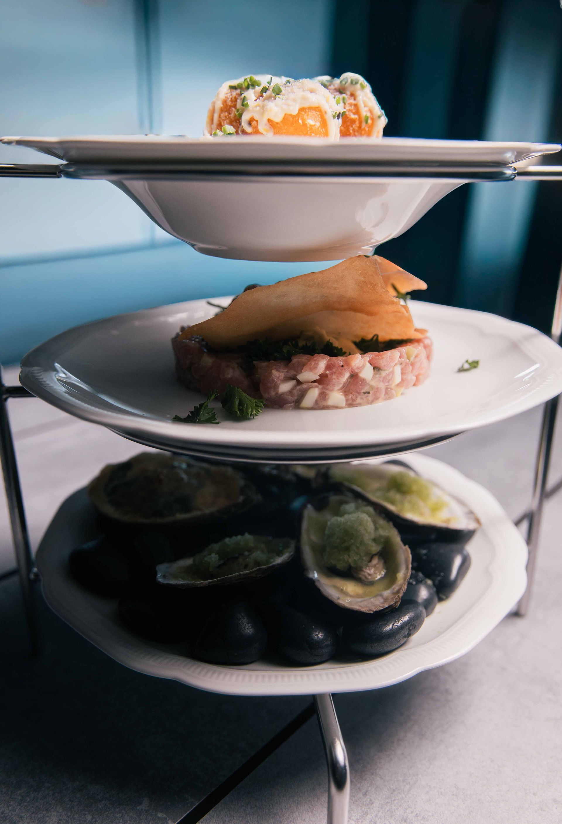 Service à étages avec amuse-gueules : pétoncles, tartare avec garniture croustillante et boulettes frites.