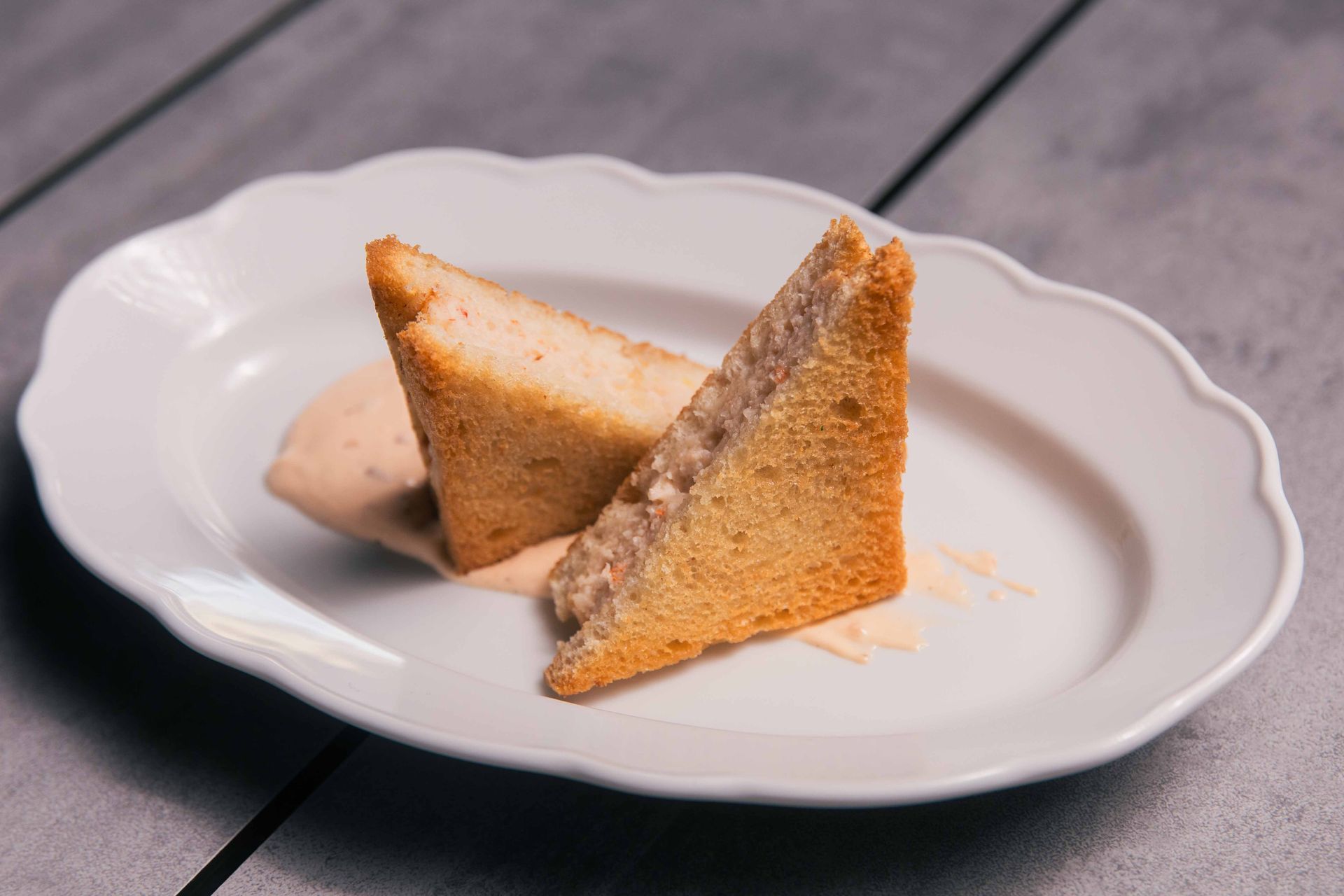 Deux sandwichs triangulaires sur une assiette blanche avec de la sauce.