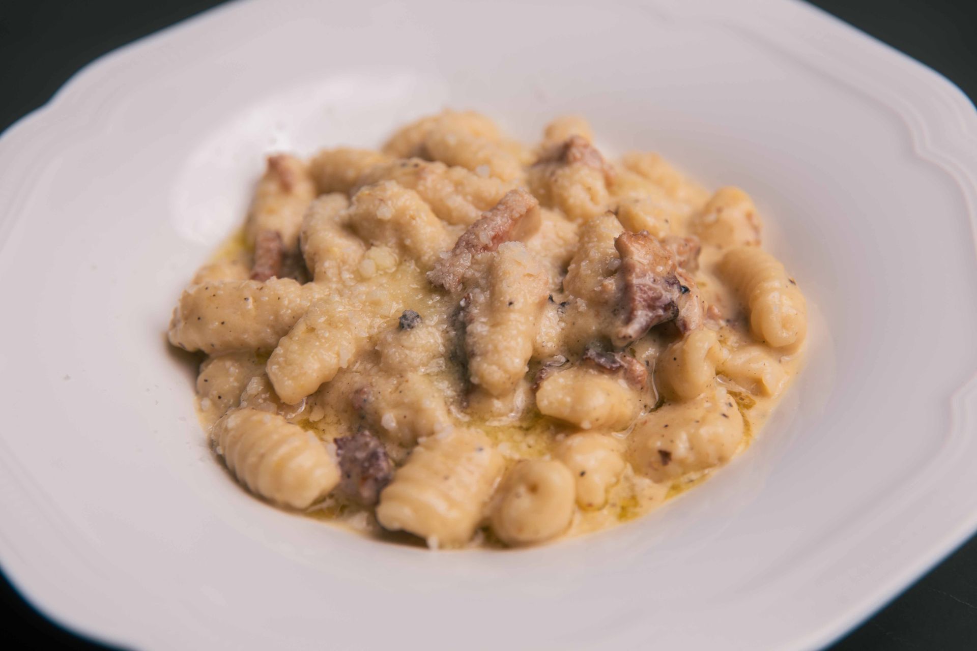 Plat de gnocchis avec une sauce crémeuse et des morceaux de viande, servi dans un bol blanc.