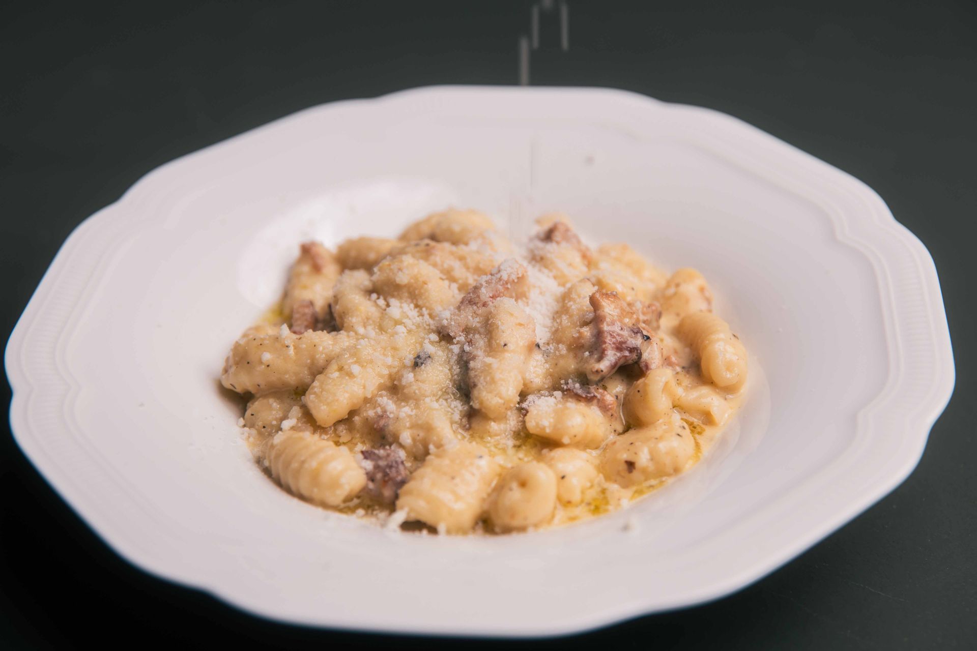 Des gnocchis à la sauce et au bacon, saupoudrés de parmesan, servis dans un bol blanc.