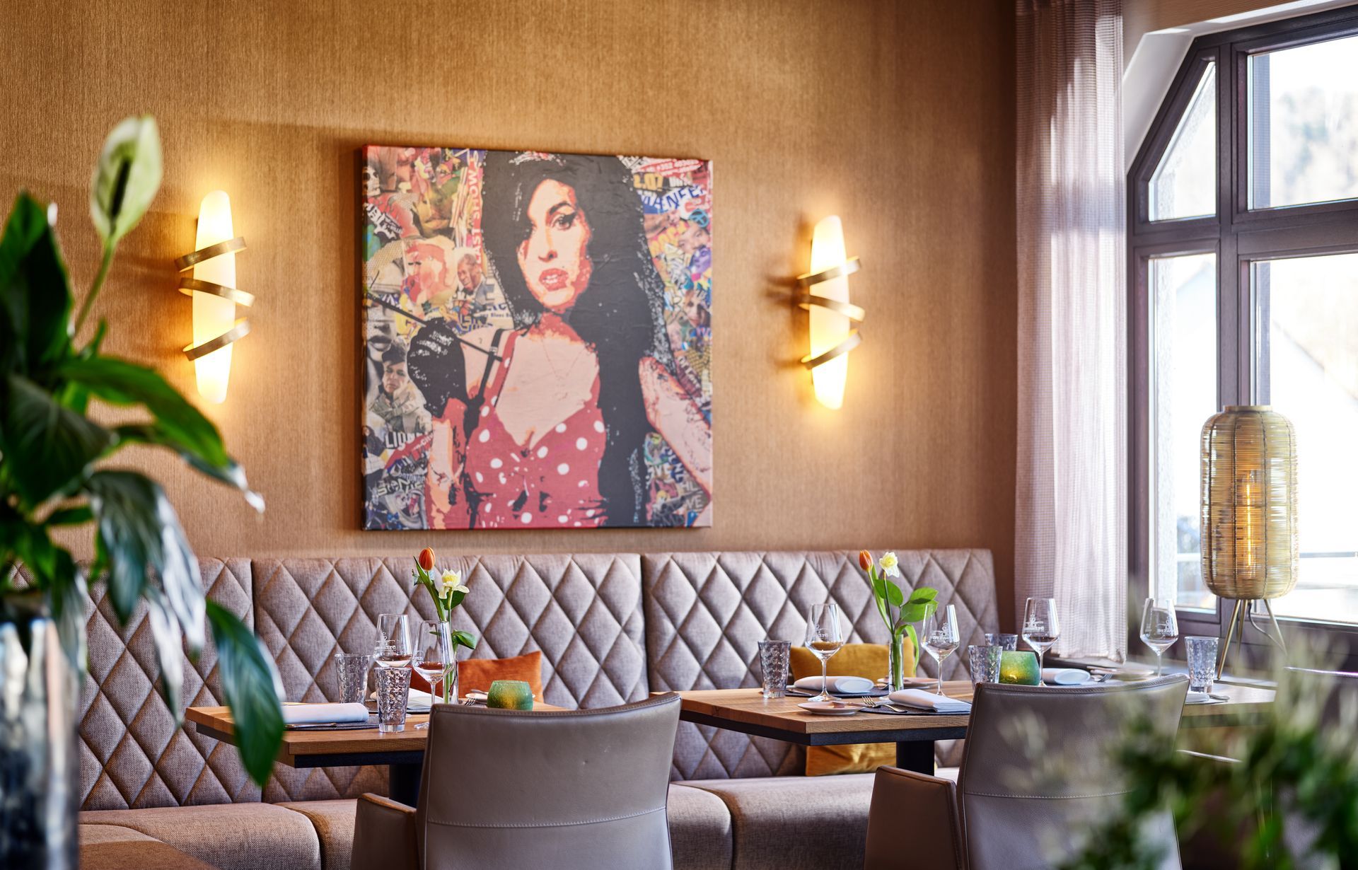 Gemütliche Restaurantnische mit gepolsterten Bänken, Holzwänden und einem farbenfrohen Porträt über den Sitzgelegenheiten.