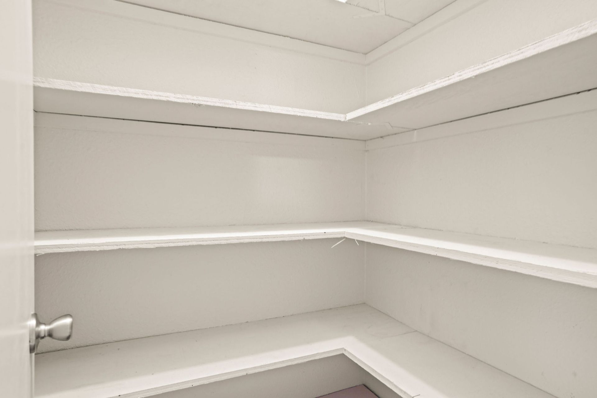 Empty white walk-in closet with built-in shelves and hanging rods