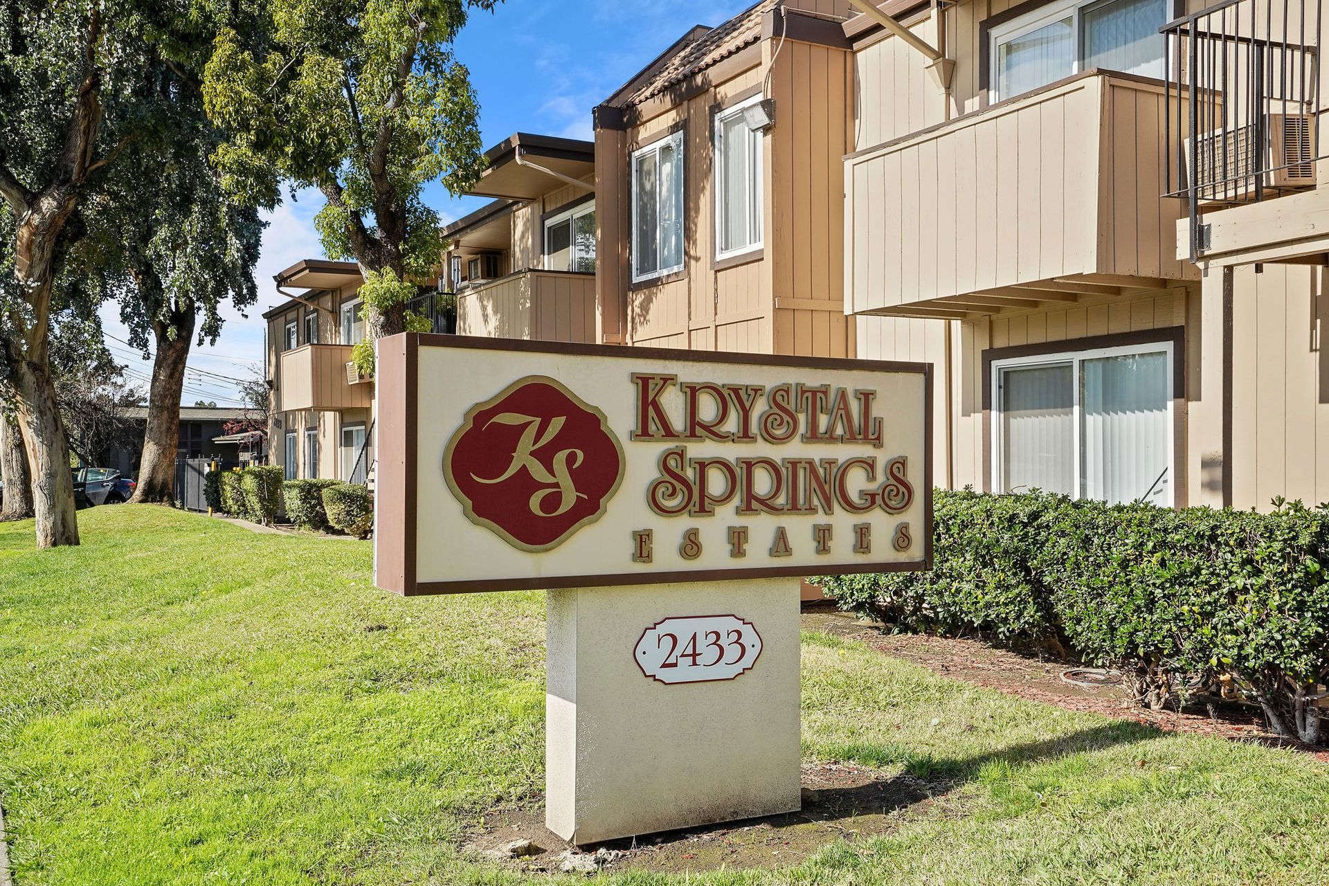Kristian Springs apartment sign in front of beige buildings and green lawn
