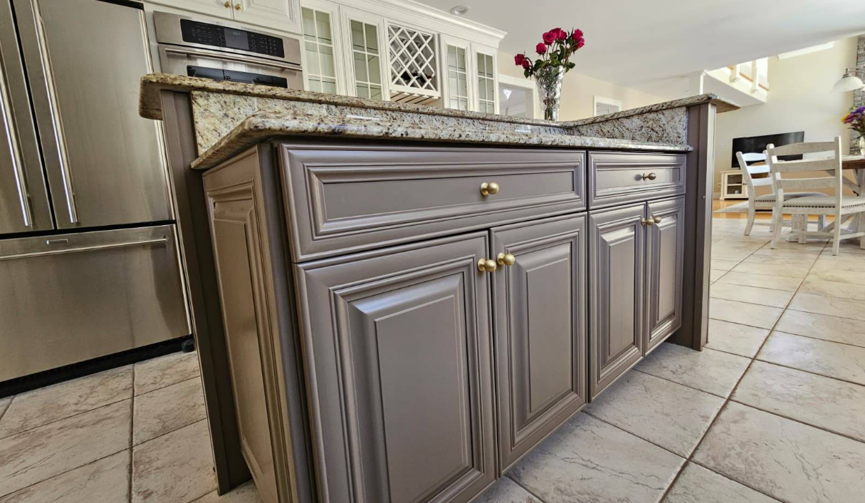 Gray kitchen island with gold handles and tiled floor in a bright home kitchen