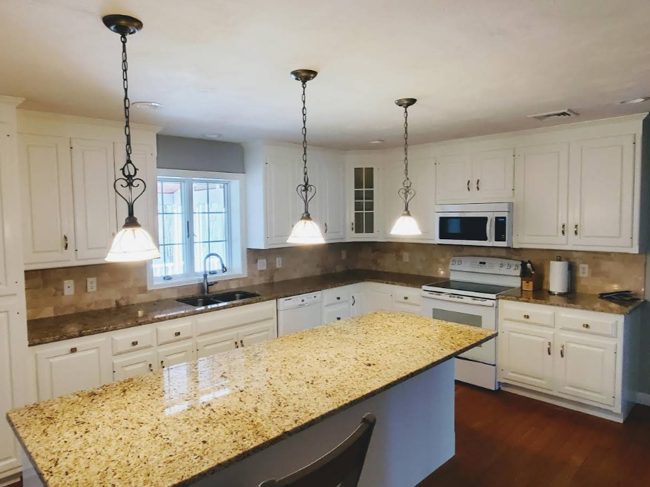 Bright modern kitchen with white cabinets, granite island, and pendant lights