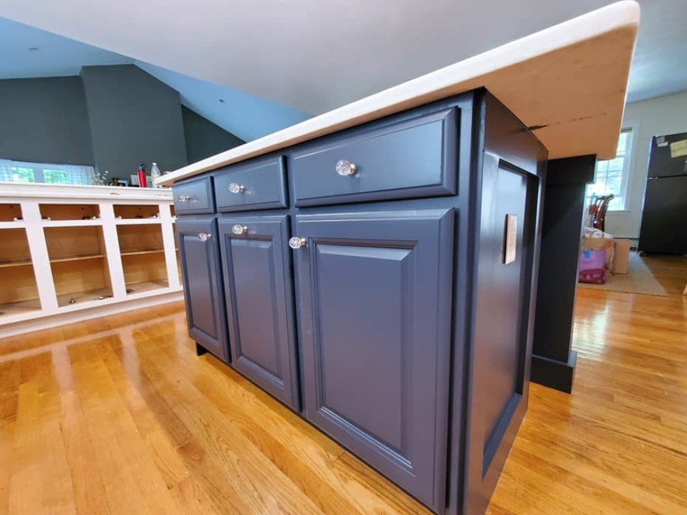 Dark blue kitchen island cabinets with drawers and doors on a hardwood floor