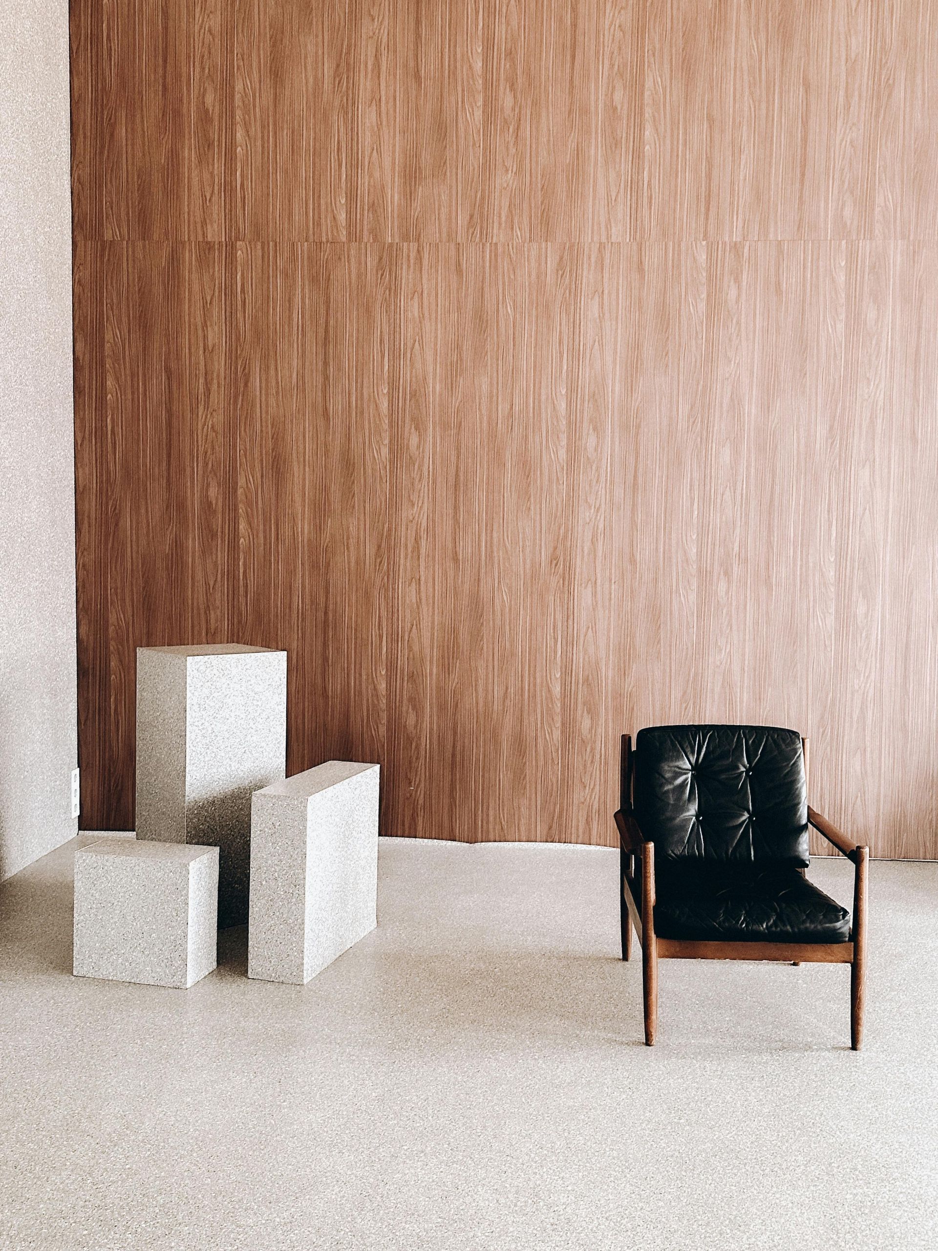 A chair is sitting in front of a wooden wall in a room.