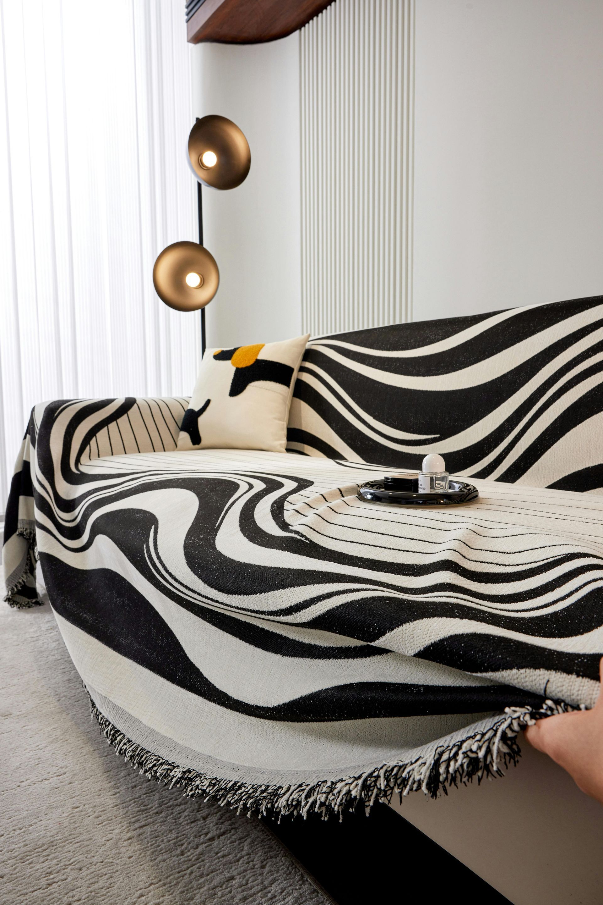A black and white zebra print blanket is covering a couch in a living room.