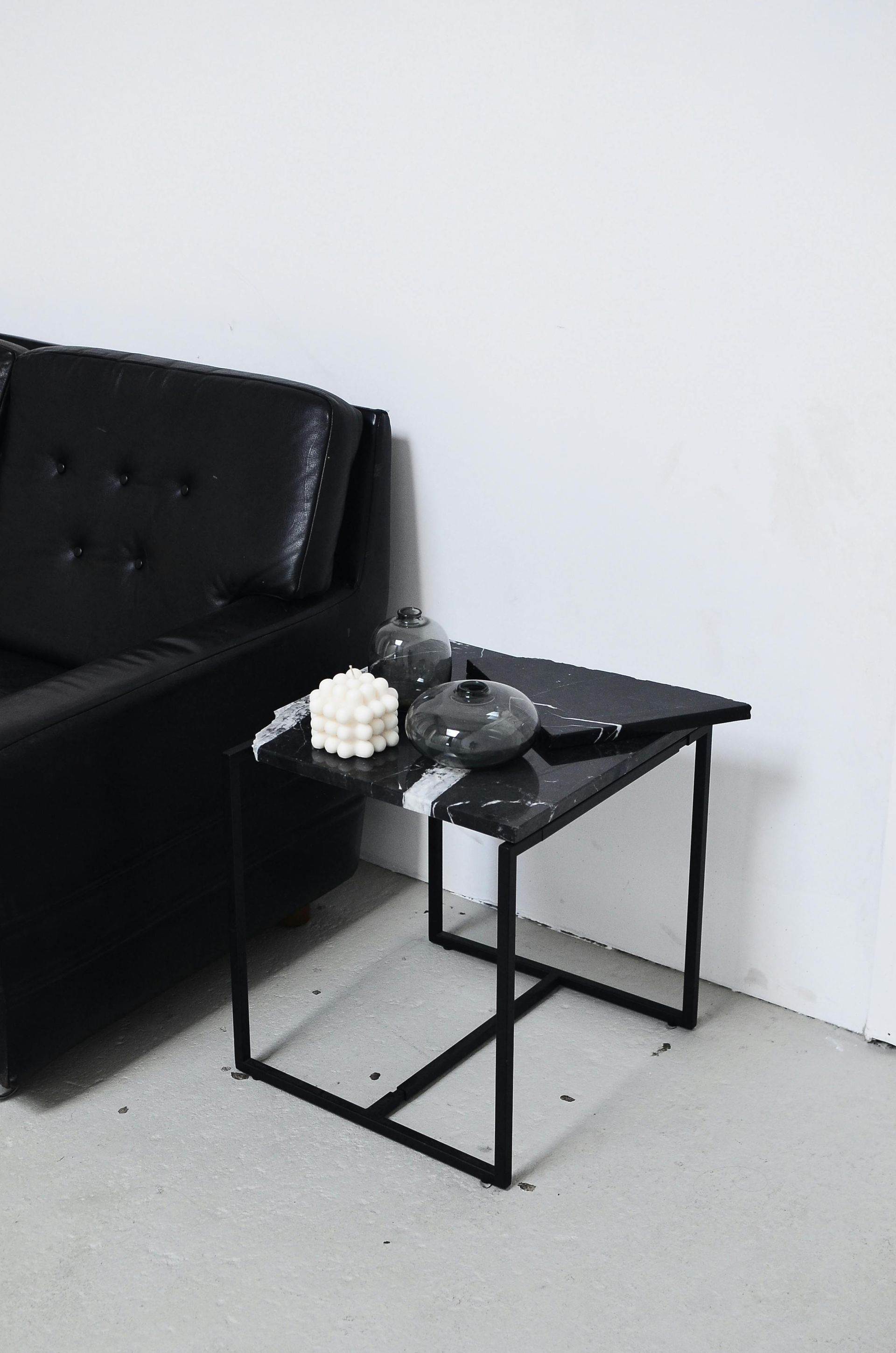 A black table is in a living room next to a black couch.