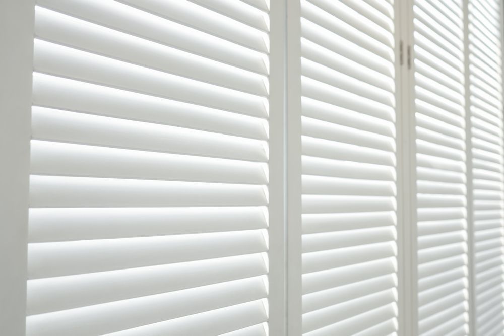 A Close Up of a Row of White Shutters on a Window — Curtain Haven & Blinds in Laurieton, NSW