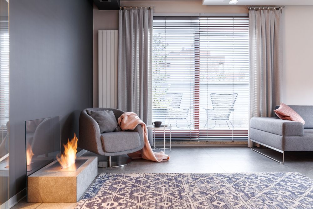 A Living Room With a Fireplace, Couch, Chair and Rug — Curtain Haven & Blinds in Laurieton, NSW