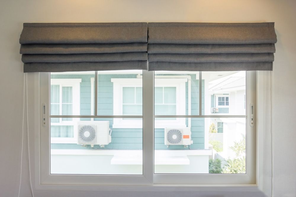 There Are Two Air Conditioners on the Side of the House Behind the Window — Curtain Haven & Blinds in Laurieton, NSW