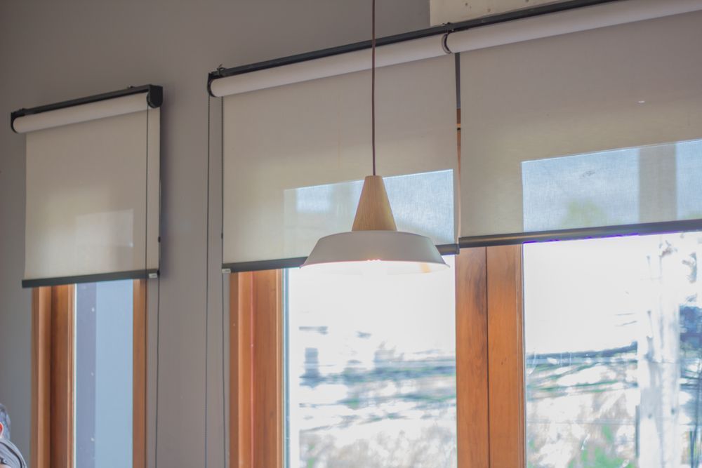 There are two windows with blinds and a lamp hanging from the ceiling — Curtain Haven & Blinds in Laurieton, NSW