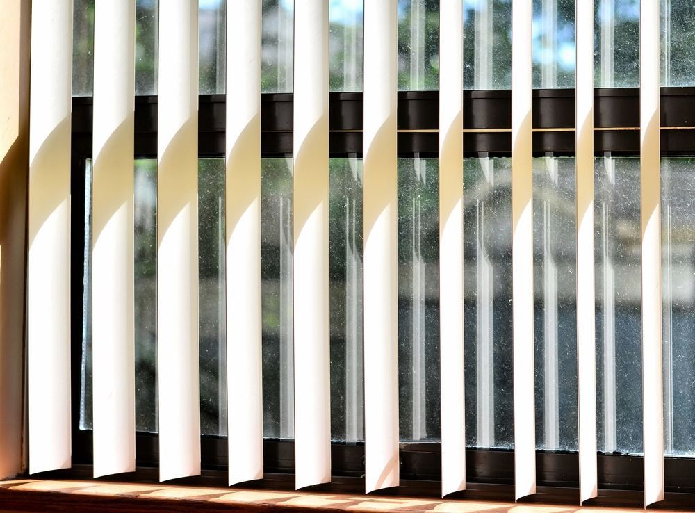A Window With White Vertical Blinds on It — Curtain Haven & Blinds in Laurieton, NSW