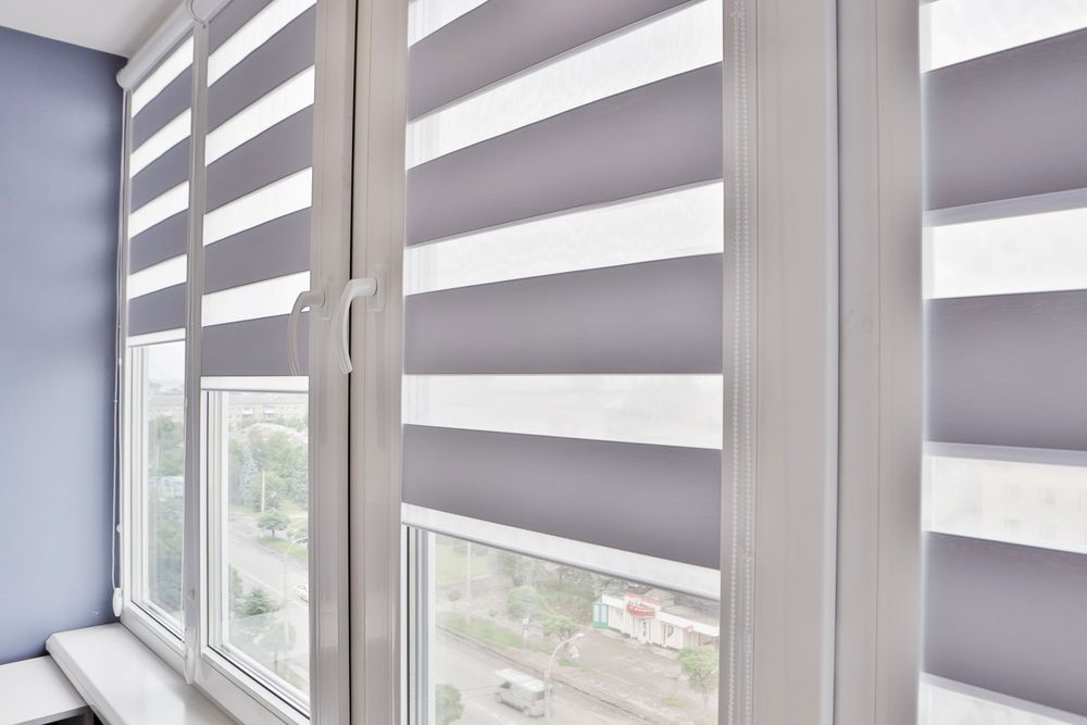 A Close Up of a Window With Striped Blinds on It — Curtain Haven & Blinds in Laurieton, NSW