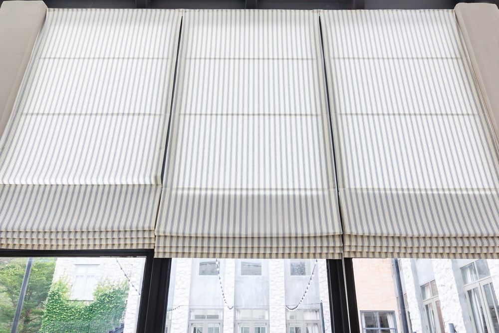 A Close Up of a Window With Roman Shades on It — Curtain Haven & Blinds in Wauchope, NSW