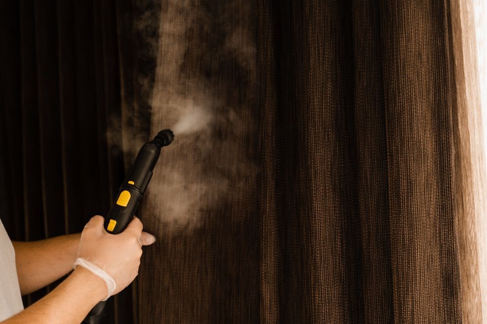 Person Using a Steam Cleaner on Brown Curtains