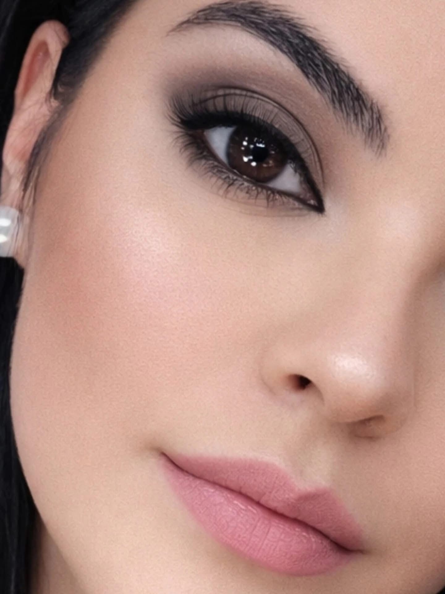 Retrato en primer plano de Lourdes con maquillaje de ojos ahumado y lápiz labial rosa, suavemente iluminado.