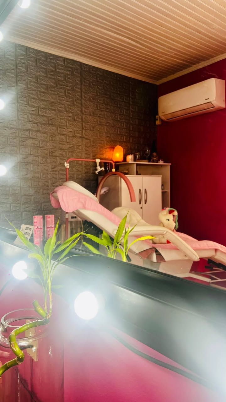 Habitación con poca luz, una cama rosa, luces brillantes, plantas, un armario y aire acondicionado.