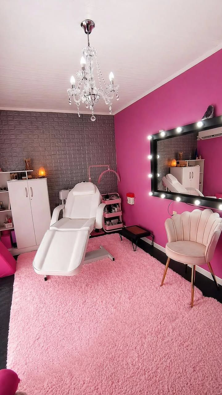 Salón de belleza rosa con sillón de masaje, lámpara de araña, espejo de tocador y alfombra rosa mullida.