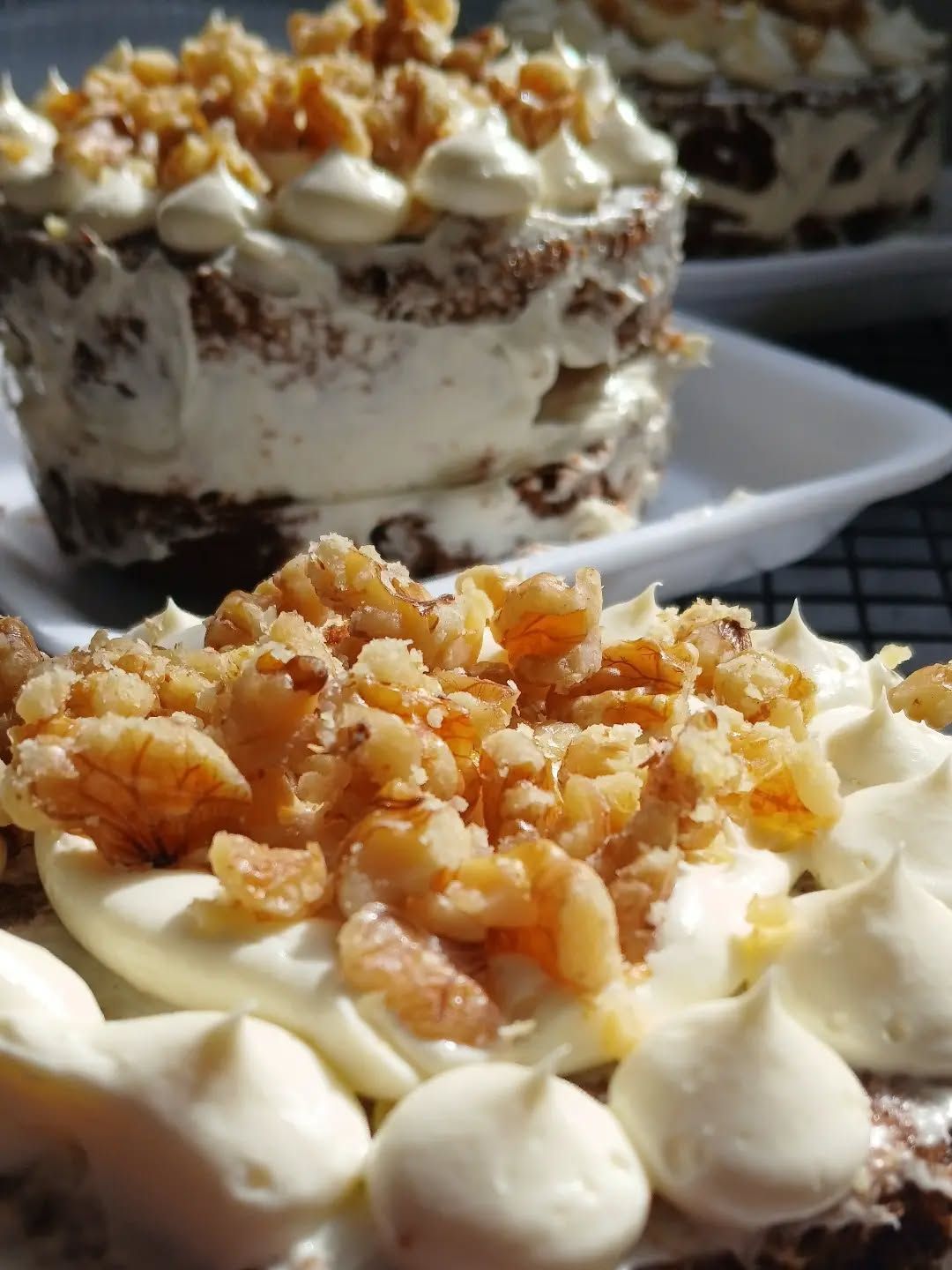Primer plano de copas de postre en capas cubiertas con crema batida y nueces trituradas.