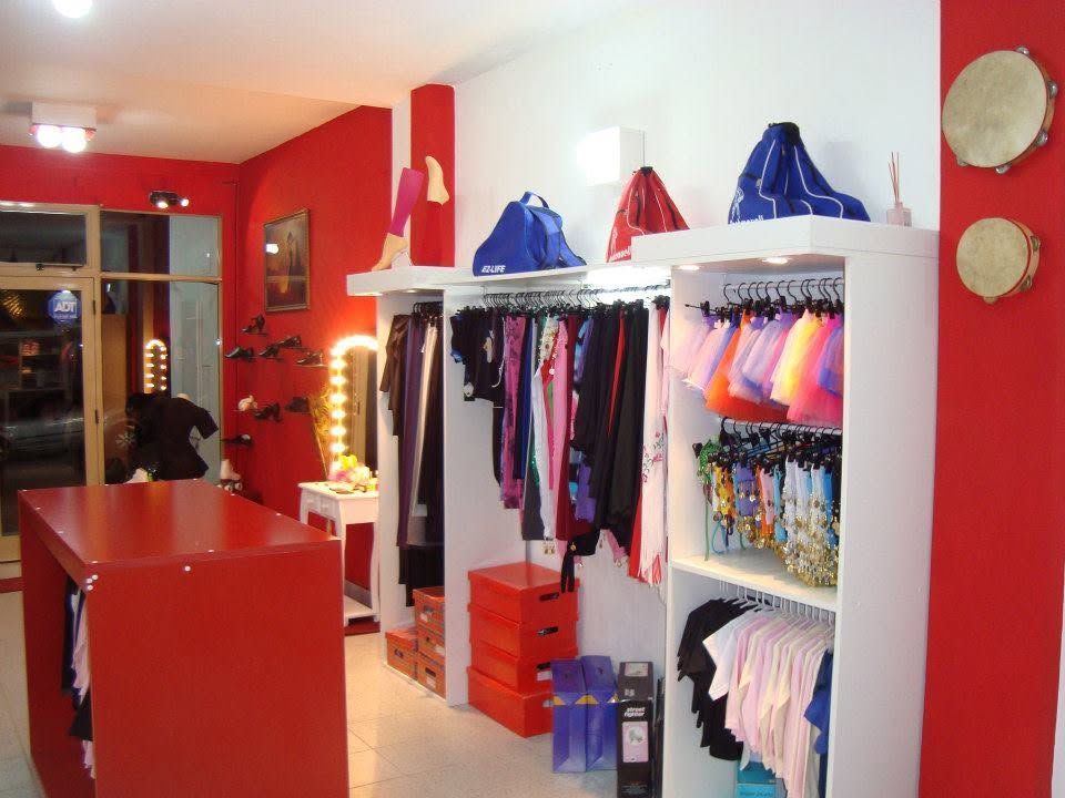Boutique de ropa roja con percheros de prendas y accesorios en un interior luminoso y moderno.