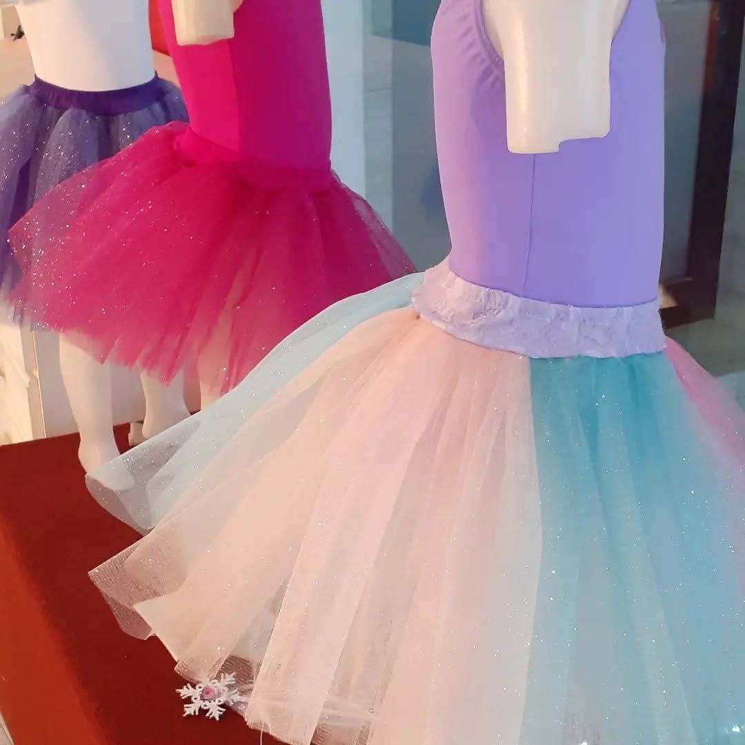 Maniquíes coloridos con vestidos de ballet brillantes, incluyendo tutús rosas, morados y azul claro.
