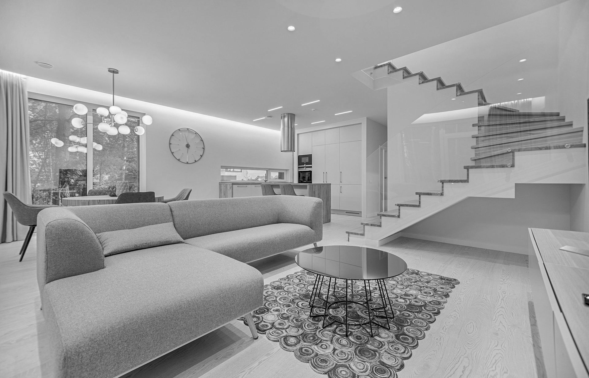 Modern living room with sectional sofa, staircase, and coffee table. Neutral tones.