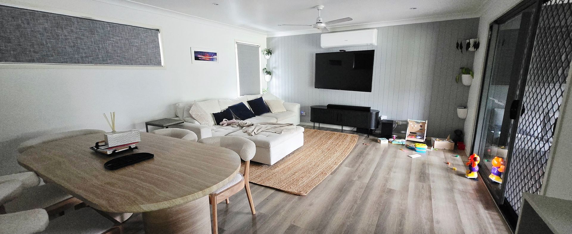 Modern living room with a couch, TV, round table, patterned rug, and large black-framed glass doors