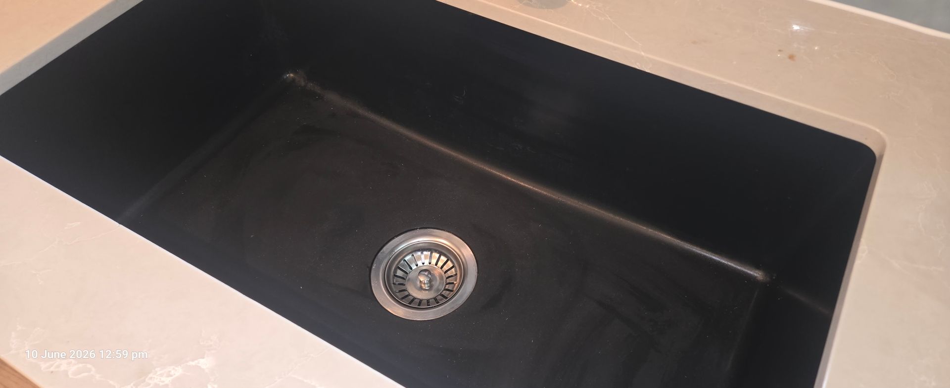 Black kitchen sink with a chrome drain centered in the basin.
