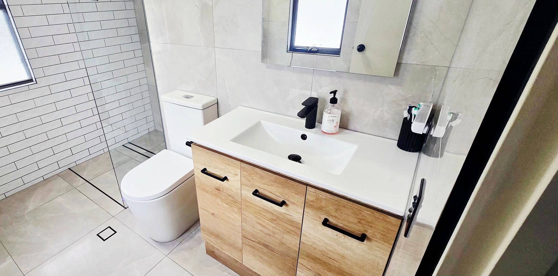 Small bathroom with toilet, vanity sink, mirror, and white tiled shower area