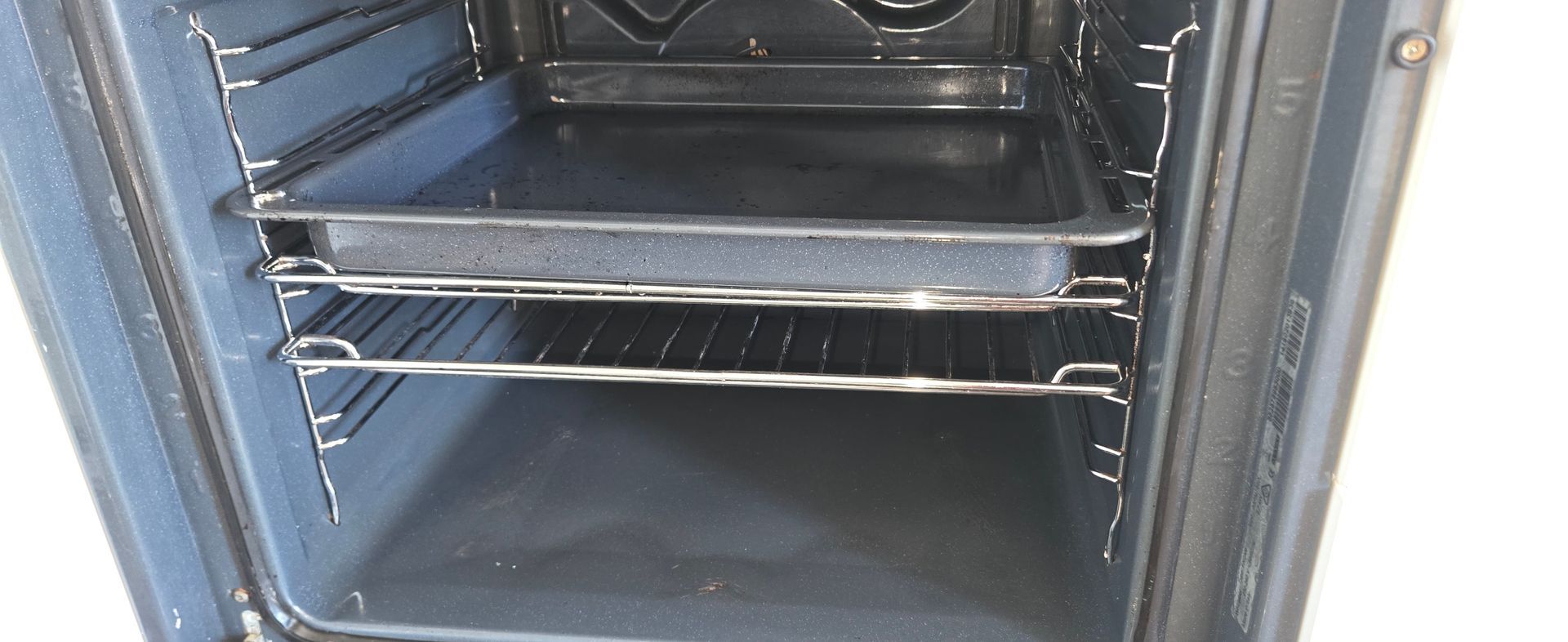 Open clean oven interior with two wire racks and a dark baking tray.