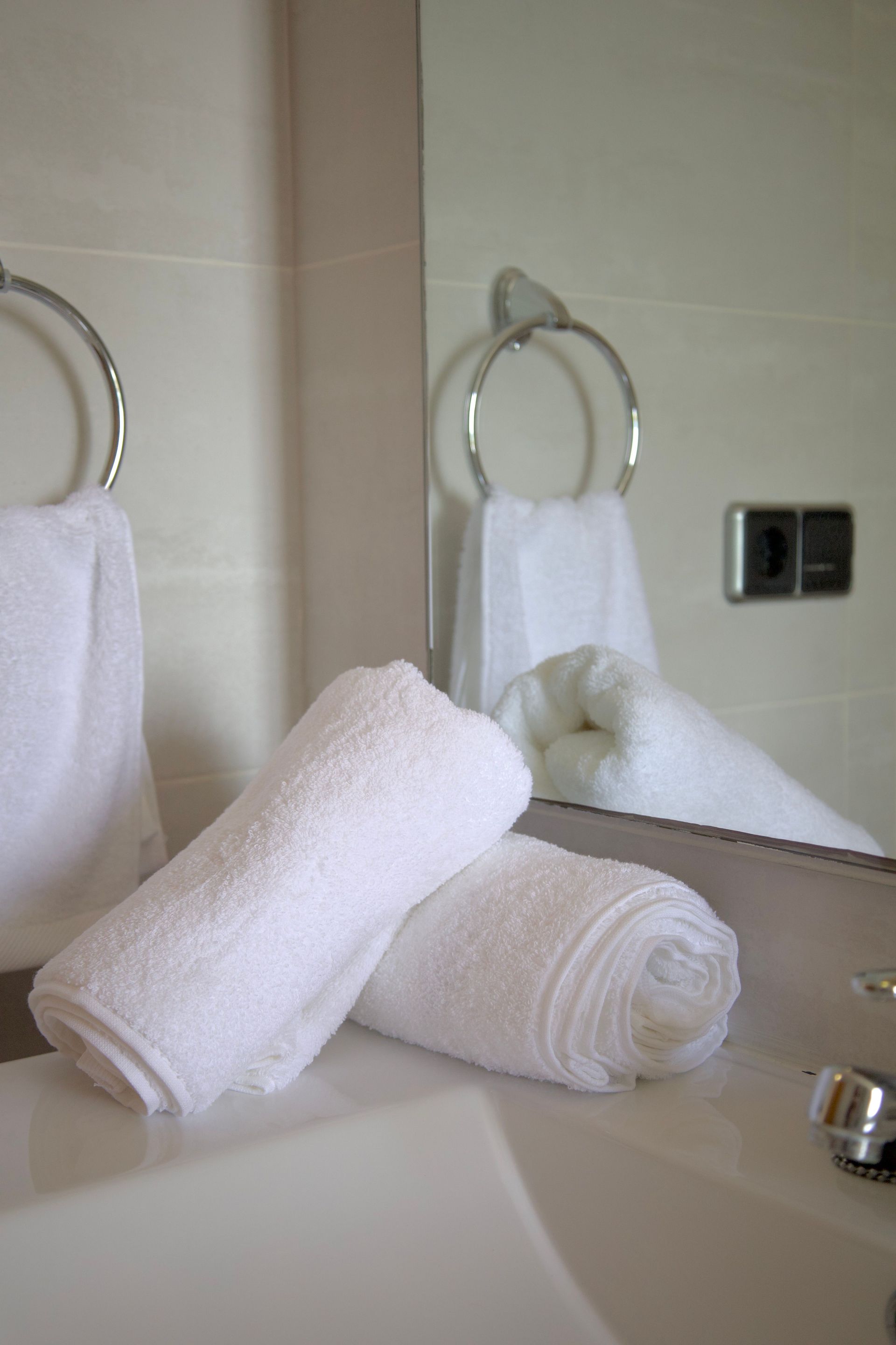 Folded white towels on a bathroom counter beside a sink and mirror.