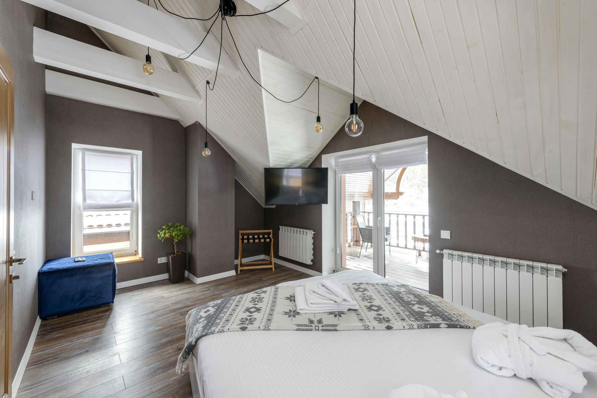 Cozy loft bedroom with vaulted ceiling, fireplace, bed, and large windows overlooking a balcony