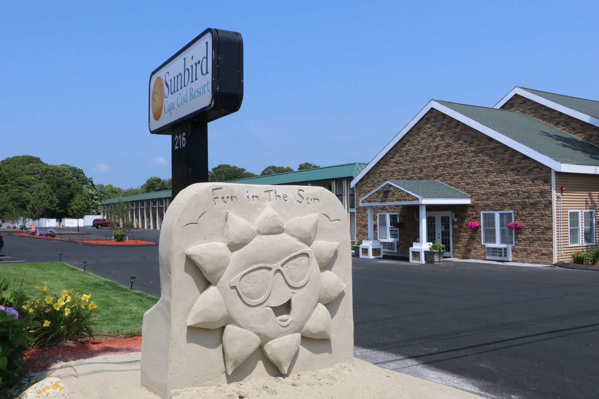 Sign for Sunbird Beach Resort with a smiling sun sculpture.