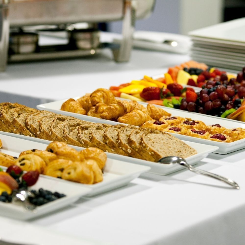 Buffet table with bread, croissants, fruit, and chafing dishes.