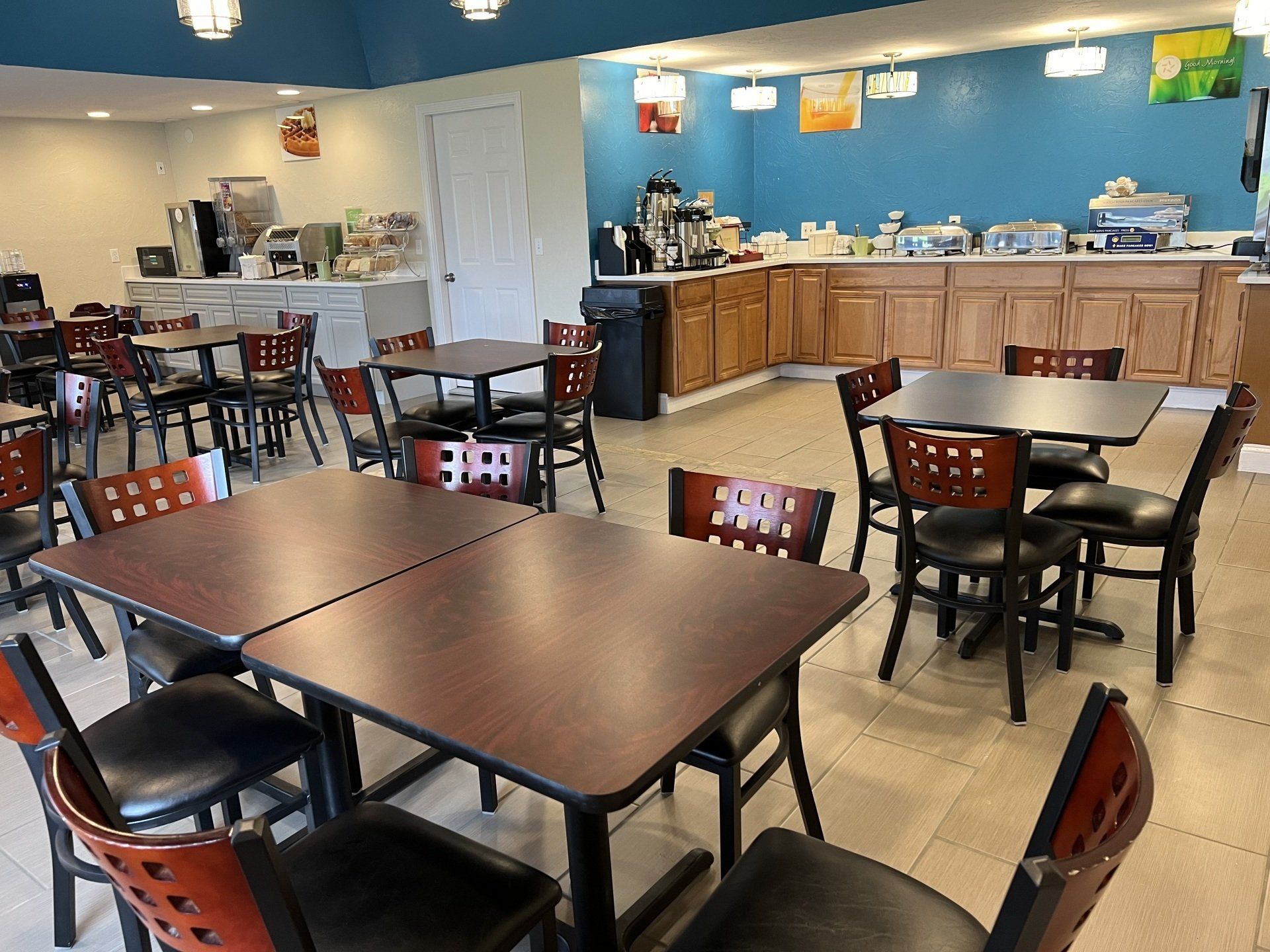 Breakfast area with tables, chairs, and buffet. Blue and tan color scheme.
