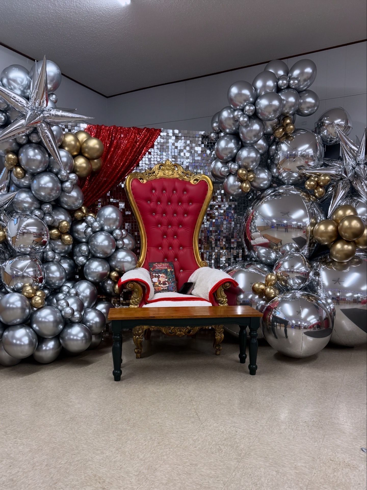A red Santa chair framed by silver and gold balloon decor