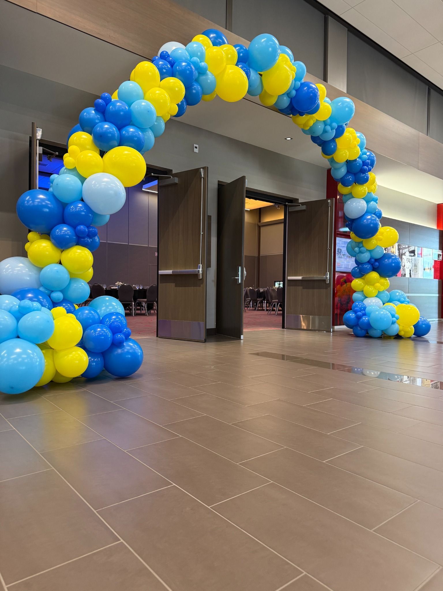Blue and yellow organic balloon arch in a spacious lobby