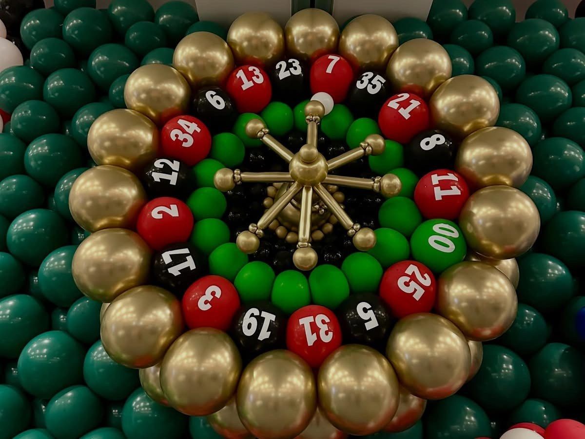 Casino roulette wheel sculpture with red, black and gold numbered pockets and a green center
