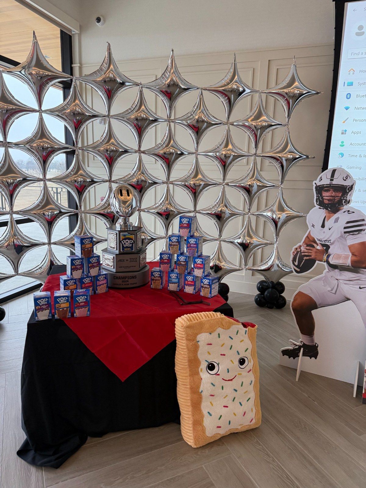 Sports-themed event table display with a trophy, snack boxes and character standee