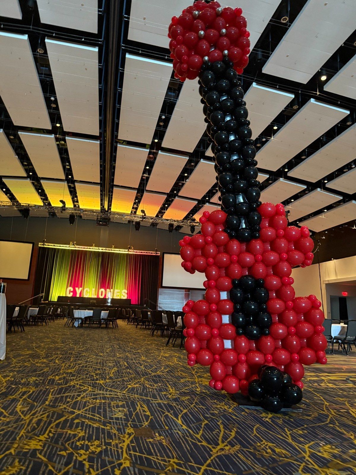 Giant red and black balloon sculpture displayed beneath a patterned hotel lobby ceiling