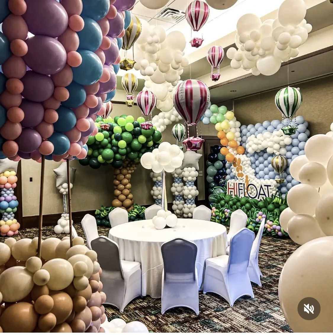 Pastel hot air balloon sculptures above tables in a decorated event room